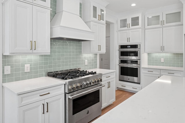 2006 Riverbend Dr, Charleston, SC 29412 - kitchen with stainless steel appliances, custom exhaust hood, backsplash, white cabinets, and light wood finished floors
