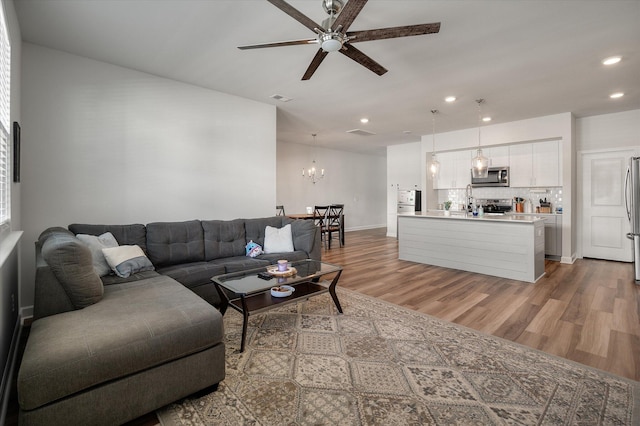 living room with hardwood / wood-style floors and ceiling fan with notable chandelier