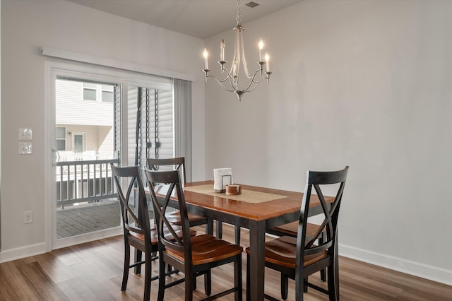 dining area featuring plenty of natural light, hardwood / wood-style flooring, and an inviting chandelier