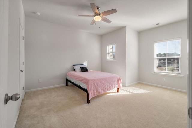 bedroom with ceiling fan, light carpet, and multiple windows