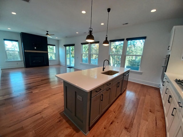 kitchen with ceiling fan, sink, an island with sink, pendant lighting, and white cabinets