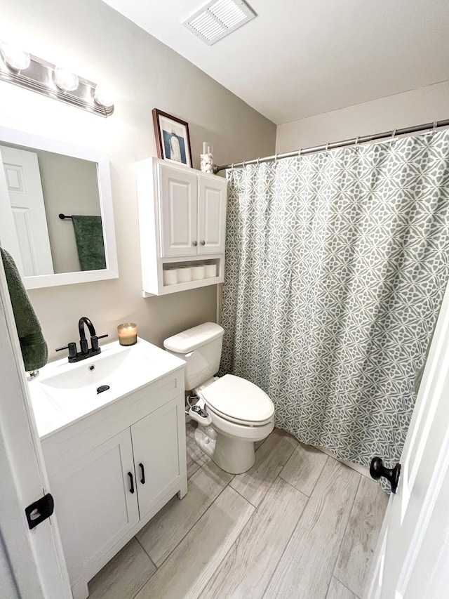 bathroom with wood finished floors, vanity, toilet, and a shower with curtain