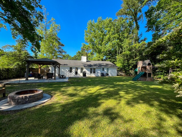 back of property with a fire pit, a gazebo, a playground, a patio area, and a chimney