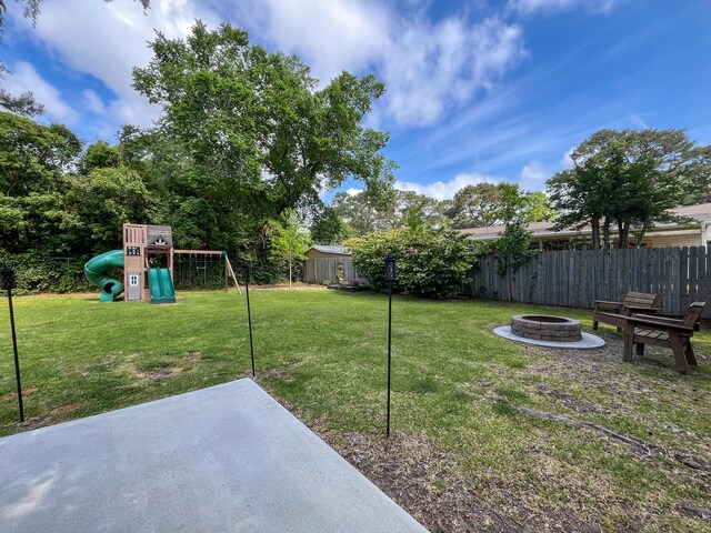 view of yard featuring a playground, a fire pit, and a patio