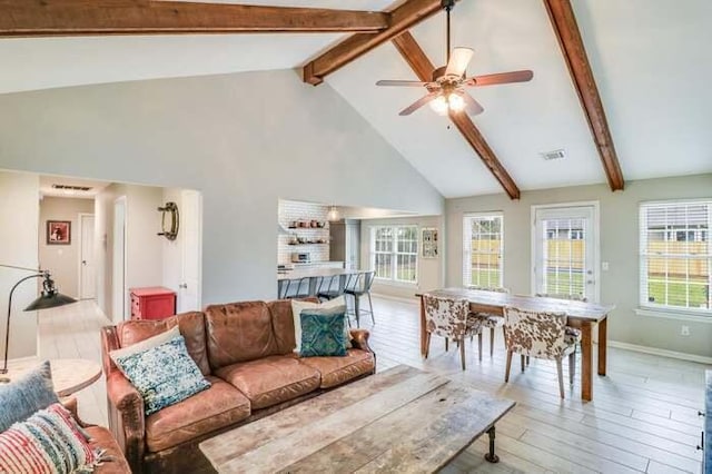 living area featuring beam ceiling, light wood finished floors, ceiling fan, baseboards, and high vaulted ceiling