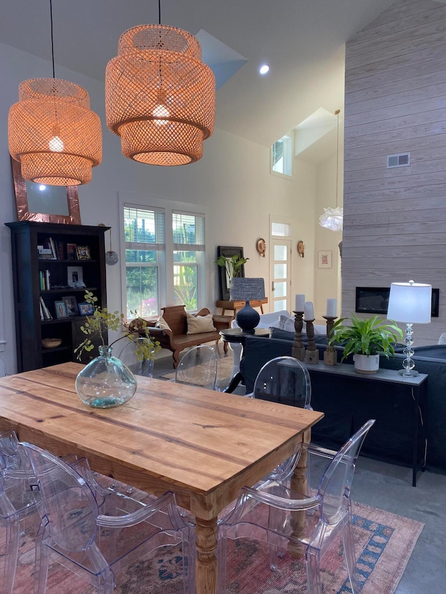 dining room featuring a fireplace and high vaulted ceiling