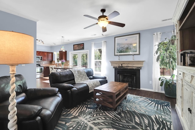 living room with visible vents, baseboards, dark wood-style flooring, a ceiling fan, and a fireplace