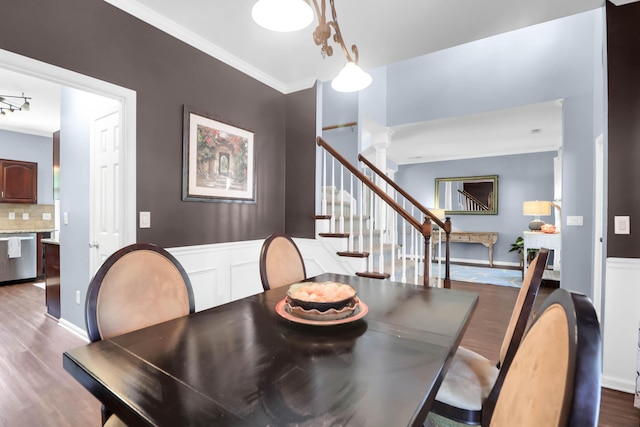 dining area featuring wood finished floors, baseboards, ornamental molding, and stairs