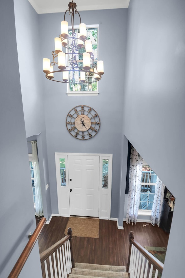 foyer with a high ceiling, wood finished floors, a notable chandelier, and baseboards