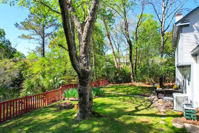view of yard with central air condition unit, a fenced backyard, and an outdoor fire pit
