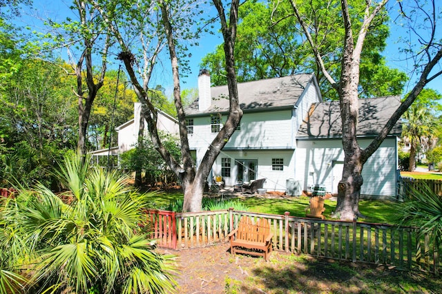 back of property with roof with shingles, a chimney, and fence