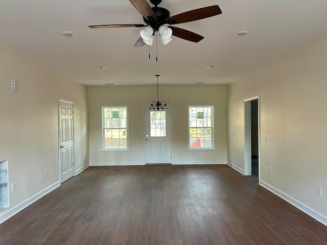 empty room with ceiling fan with notable chandelier and dark hardwood / wood-style floors