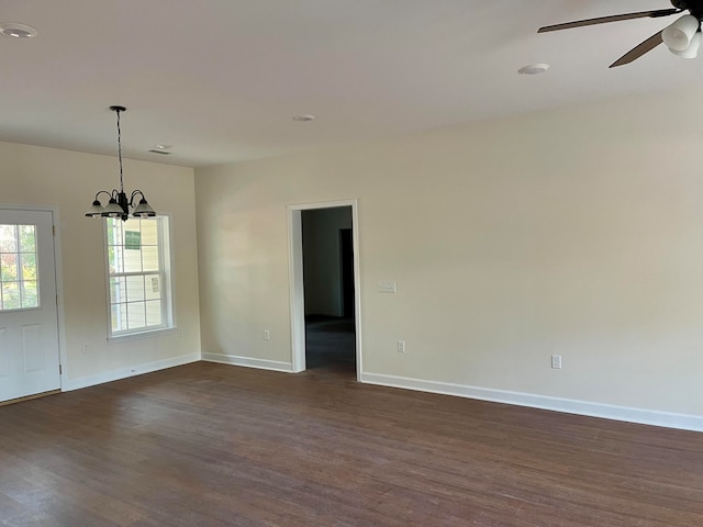 empty room with dark wood-type flooring and ceiling fan with notable chandelier