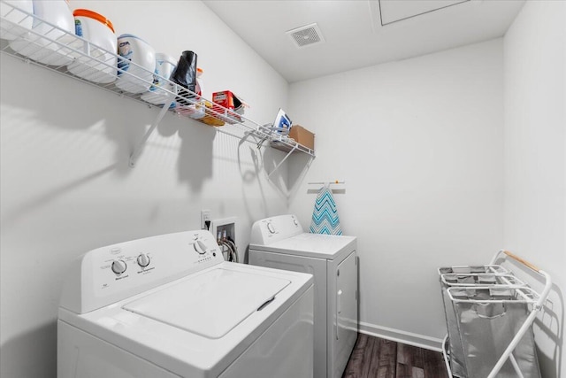 clothes washing area with visible vents, washer and clothes dryer, dark wood-style floors, baseboards, and laundry area