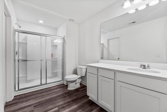 bathroom with vanity, wood finished floors, visible vents, a shower stall, and toilet