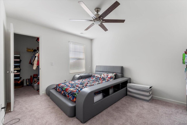 carpeted bedroom with visible vents, a walk in closet, ceiling fan, baseboards, and a closet