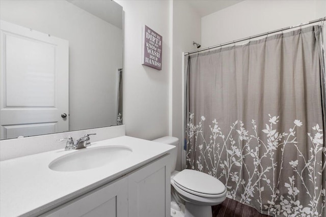 bathroom featuring a shower with curtain, toilet, wood finished floors, and vanity