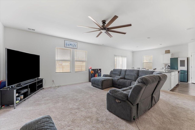 living area with visible vents, ceiling fan, and carpet