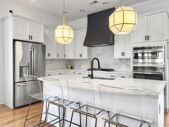 kitchen featuring light wood-style floors, appliances with stainless steel finishes, decorative backsplash, and wall chimney exhaust hood