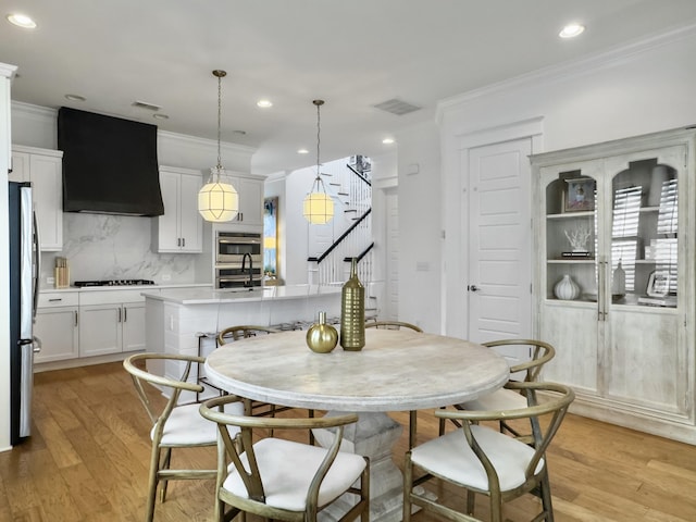 dining space featuring crown molding, stairs, visible vents, and light wood-type flooring