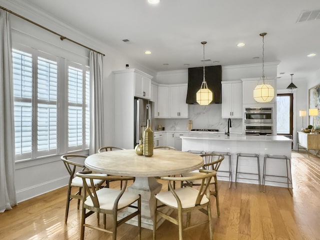 dining space with baseboards, plenty of natural light, light wood-type flooring, and visible vents