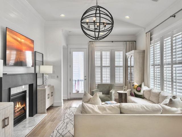 living room with an inviting chandelier, light wood finished floors, recessed lighting, a high end fireplace, and ornamental molding