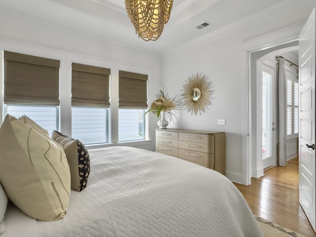 bedroom featuring visible vents, ornamental molding, baseboards, light wood-type flooring, and a chandelier