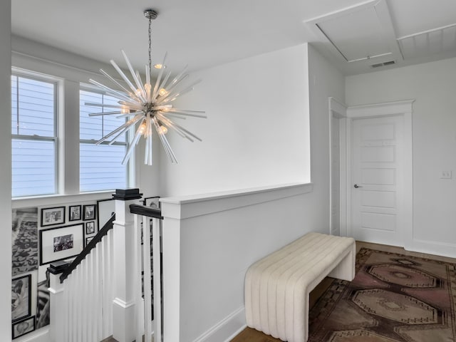 stairway with visible vents, baseboards, a chandelier, and attic access