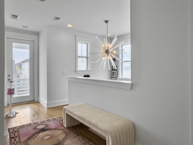 foyer entrance with baseboards, a notable chandelier, light wood-style flooring, and visible vents
