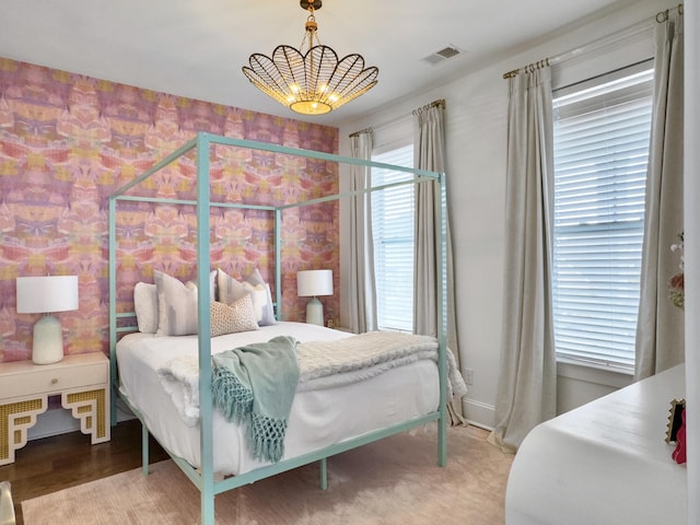 bedroom featuring an inviting chandelier, visible vents, and wallpapered walls