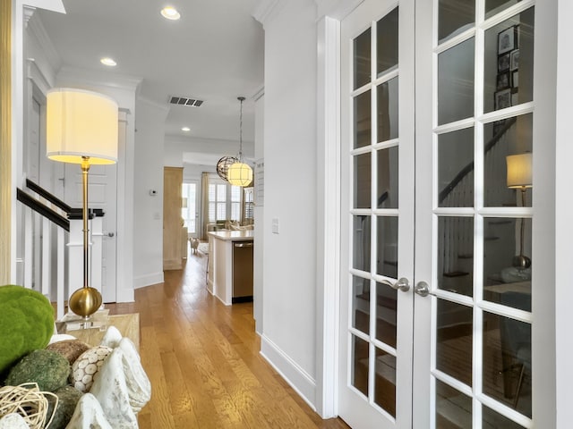 corridor with visible vents, ornamental molding, baseboards, recessed lighting, and light wood-type flooring