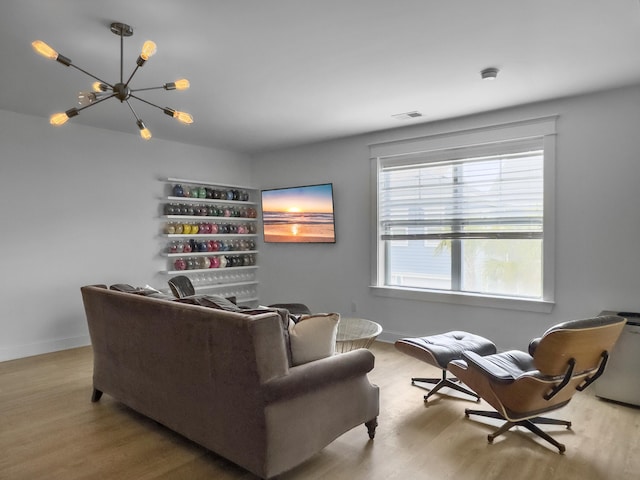 living room featuring baseboards, a chandelier, wood finished floors, and visible vents