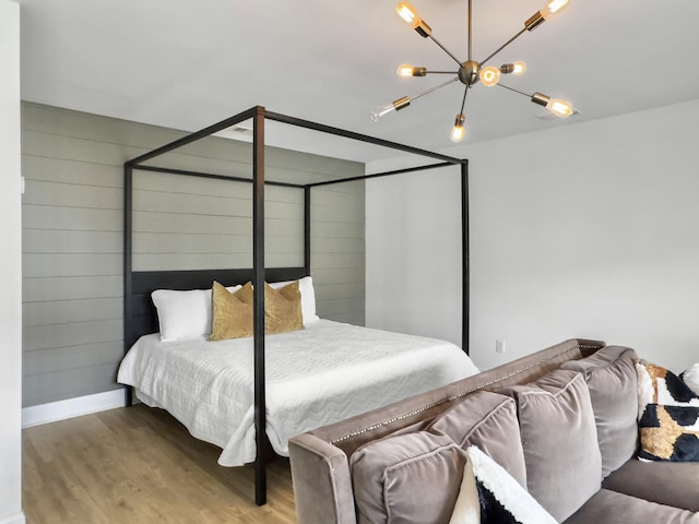 bedroom with an inviting chandelier, baseboards, and wood finished floors