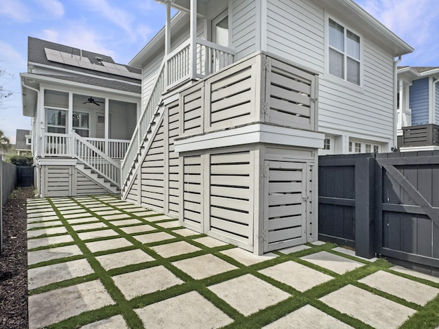 exterior space featuring fence, stairway, a gate, solar panels, and a ceiling fan