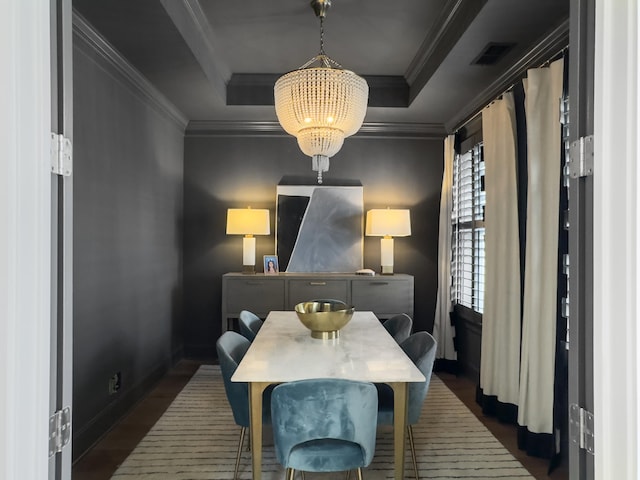 dining space with visible vents, crown molding, dark wood finished floors, an inviting chandelier, and a tray ceiling