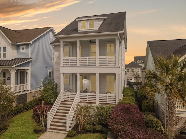 beach home featuring a porch, stairway, a balcony, and roof with shingles