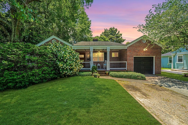 view of front of property featuring a porch, a garage, and a lawn