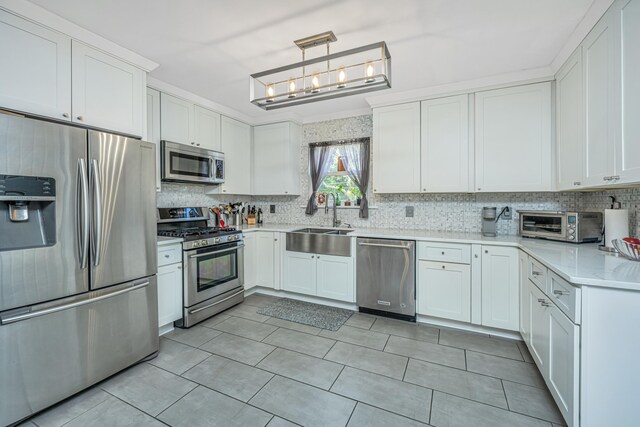 kitchen with pendant lighting, sink, appliances with stainless steel finishes, white cabinetry, and tasteful backsplash