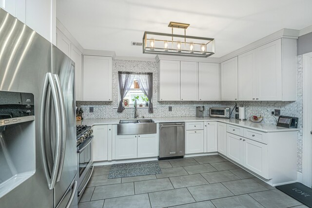 kitchen featuring white cabinetry, sink, backsplash, hanging light fixtures, and stainless steel appliances