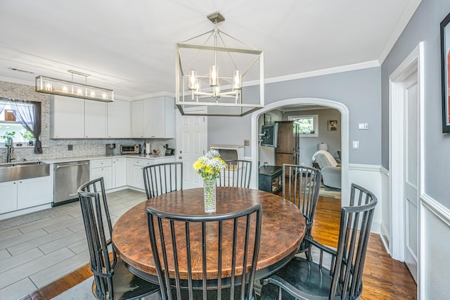 dining space featuring crown molding, sink, a notable chandelier, and light hardwood / wood-style floors