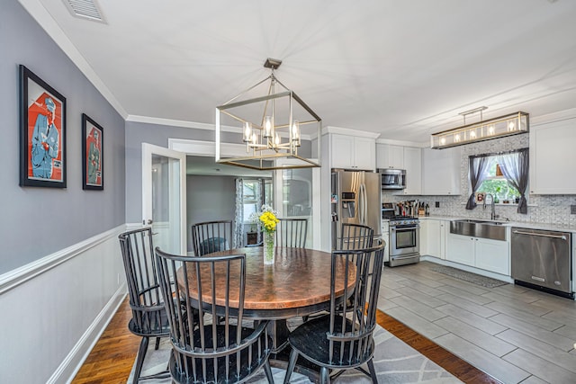 dining space featuring dark wood-type flooring, a healthy amount of sunlight, crown molding, and sink