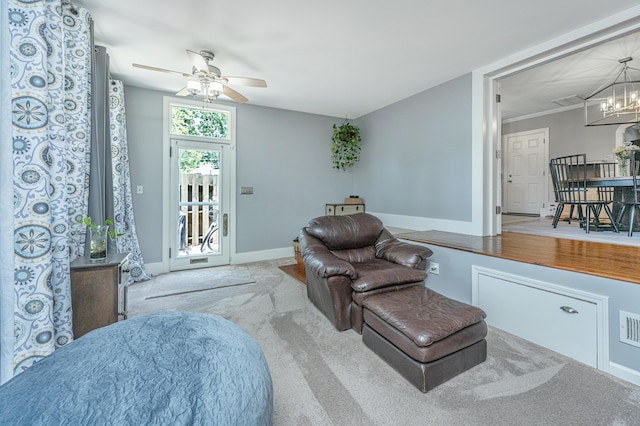 living room featuring light carpet and ceiling fan with notable chandelier