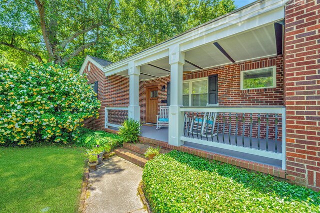 doorway to property featuring a yard and covered porch