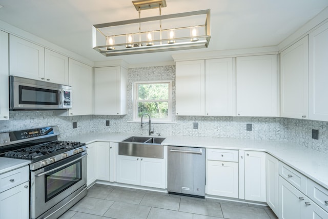 kitchen with pendant lighting, appliances with stainless steel finishes, sink, and white cabinets