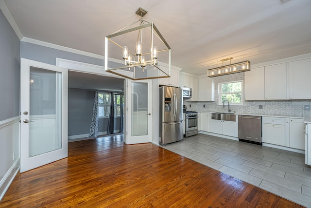 kitchen featuring hardwood / wood-style floors, decorative light fixtures, stainless steel appliances, and white cabinets