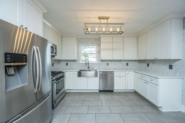 kitchen with sink, tasteful backsplash, decorative light fixtures, appliances with stainless steel finishes, and white cabinets