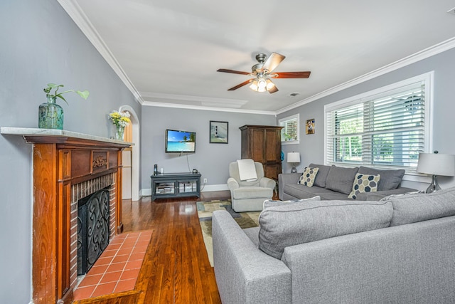 living room with crown molding, dark hardwood / wood-style floors, ceiling fan, and a fireplace