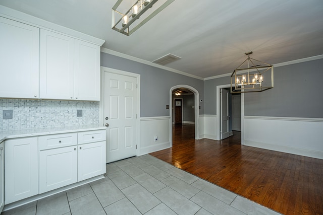 kitchen featuring white cabinetry, decorative light fixtures, light tile patterned floors, and crown molding