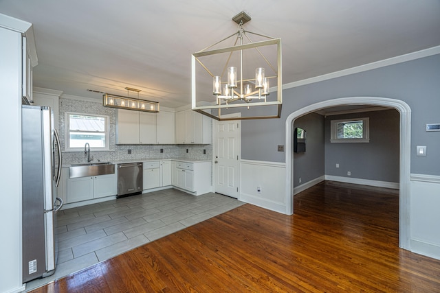 kitchen featuring sink, white cabinetry, wood-type flooring, hanging light fixtures, and stainless steel appliances