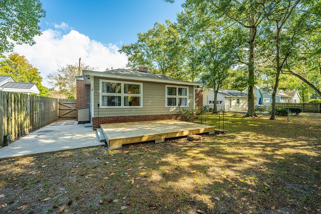 rear view of house featuring a wooden deck and a lawn